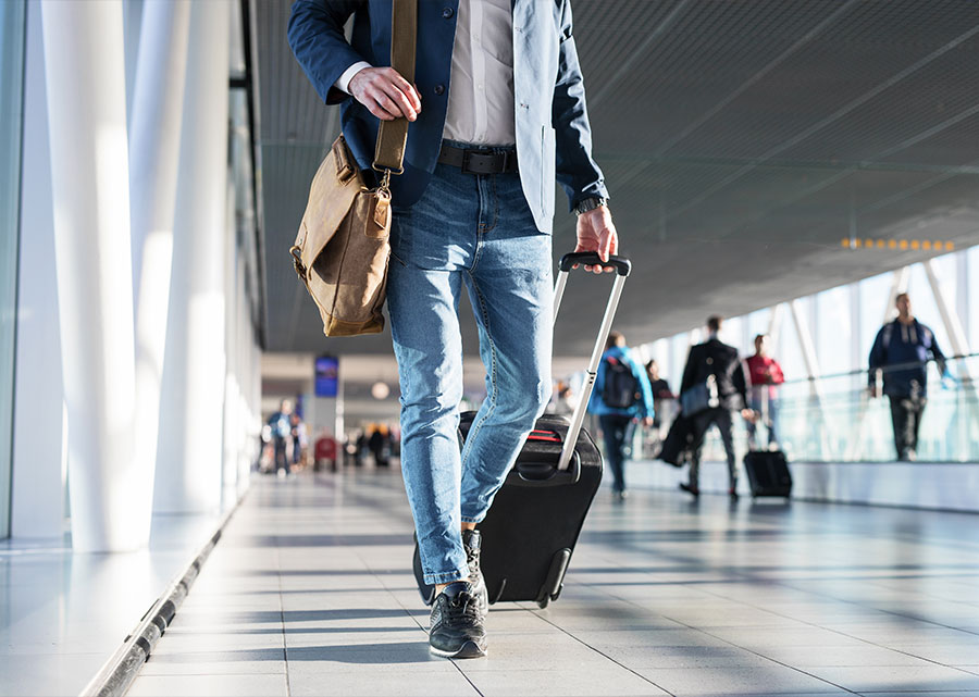 man rolls luggage through an airport terminal