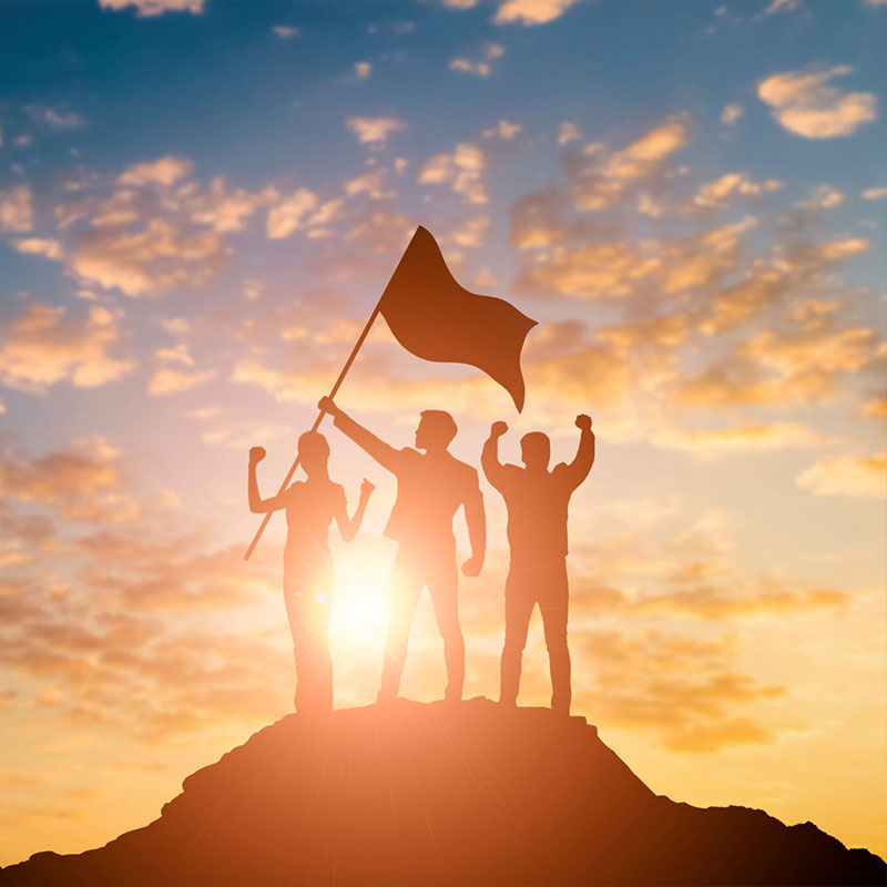 three people stand on a mountaintop holding a flag