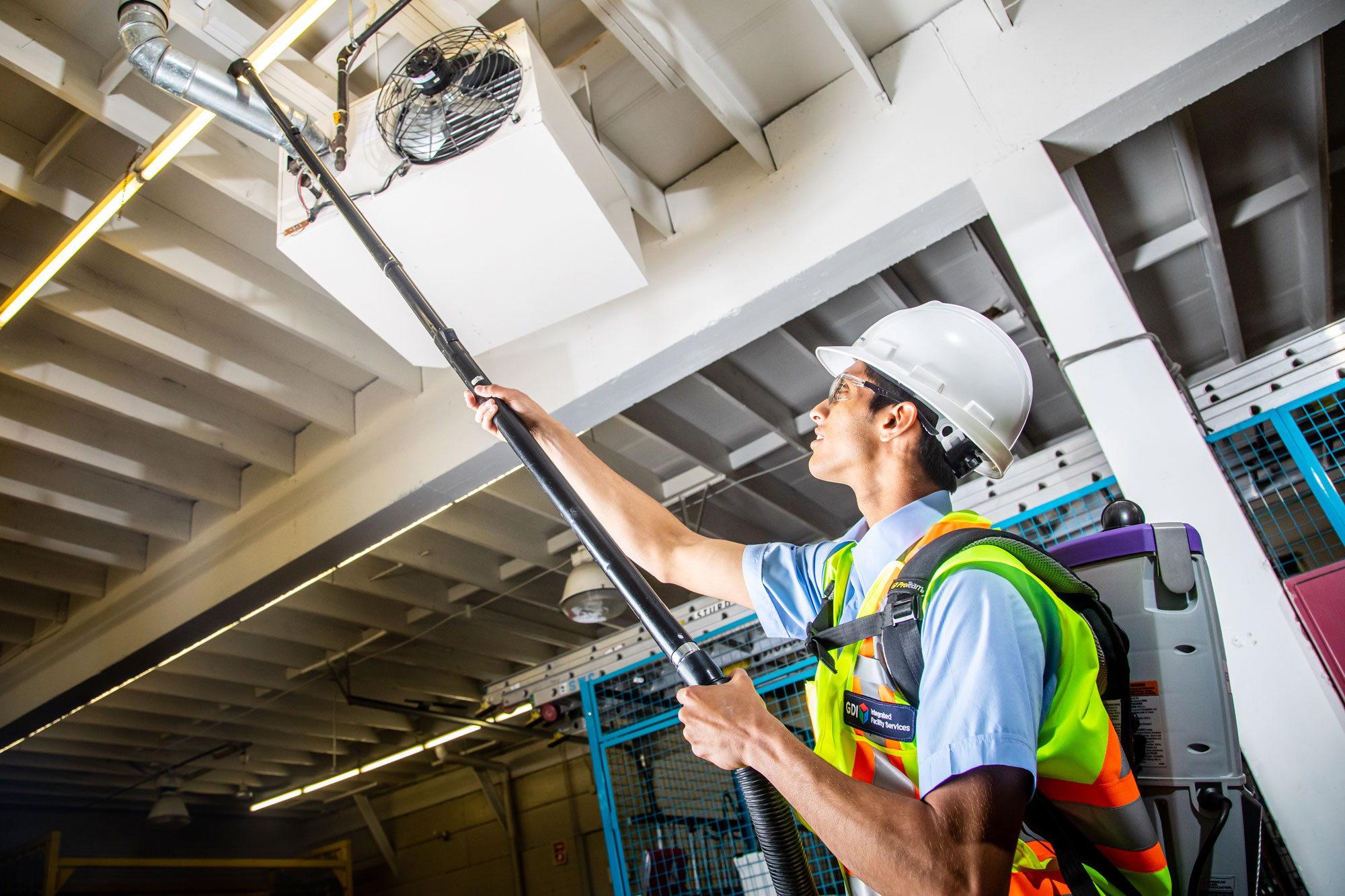 IH Services service area: a technician high-dusting overhead ductwork at an industrial site