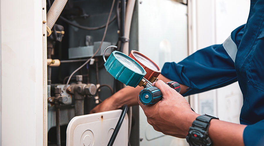 Compliance in practice: IH Services maintenance technician reading HVAC gauges on a cleared site